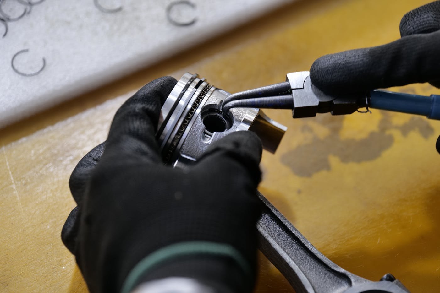 Técnico revisando un pistón y anillos de motor en taller